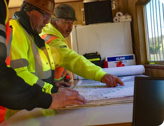 Construction professionals reviewing engineering plans during an active infrastructure project meeting.