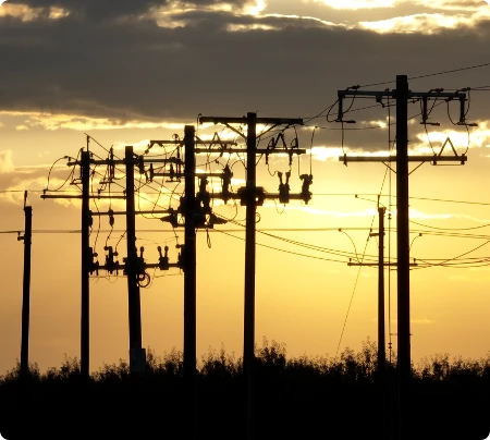Power Line Poles at Sunset Team of four construction workers in hard hats and safety vests discussing project details at an aggregate mining site with conveyor structure