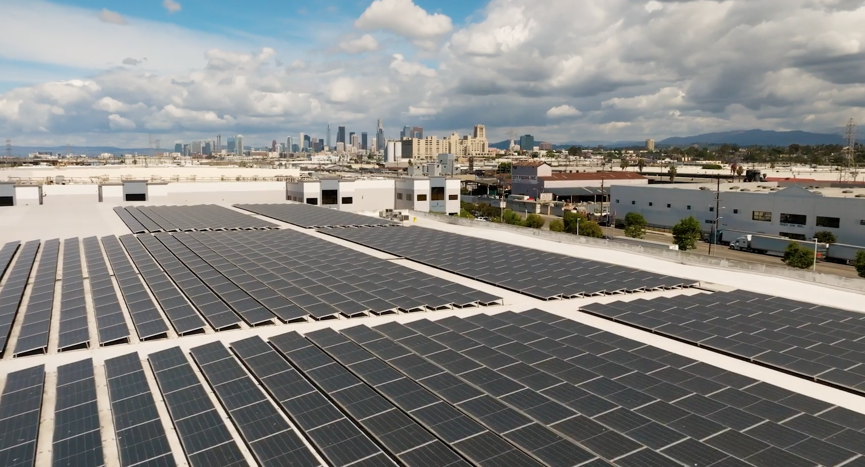 Rooftop solar array with a city skyline in the background.