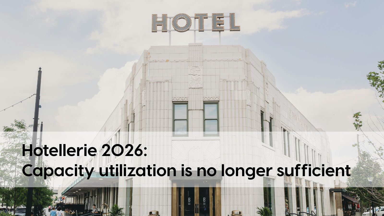 Front view of a white building with the word “Hotel” on the roof. Black lettering on a white background reads “Hotel industry 2026: Occupancy rates are no longer sufficient.” 
