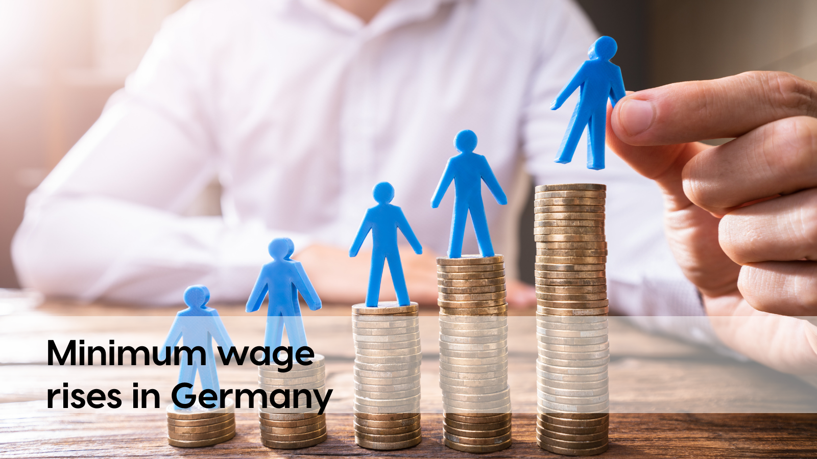 Blue figures on stacks of coins symbolize the rising minimum wage in Germany and the growing importance of cost and productivity transparency, for example through data-based analyses with profitize.