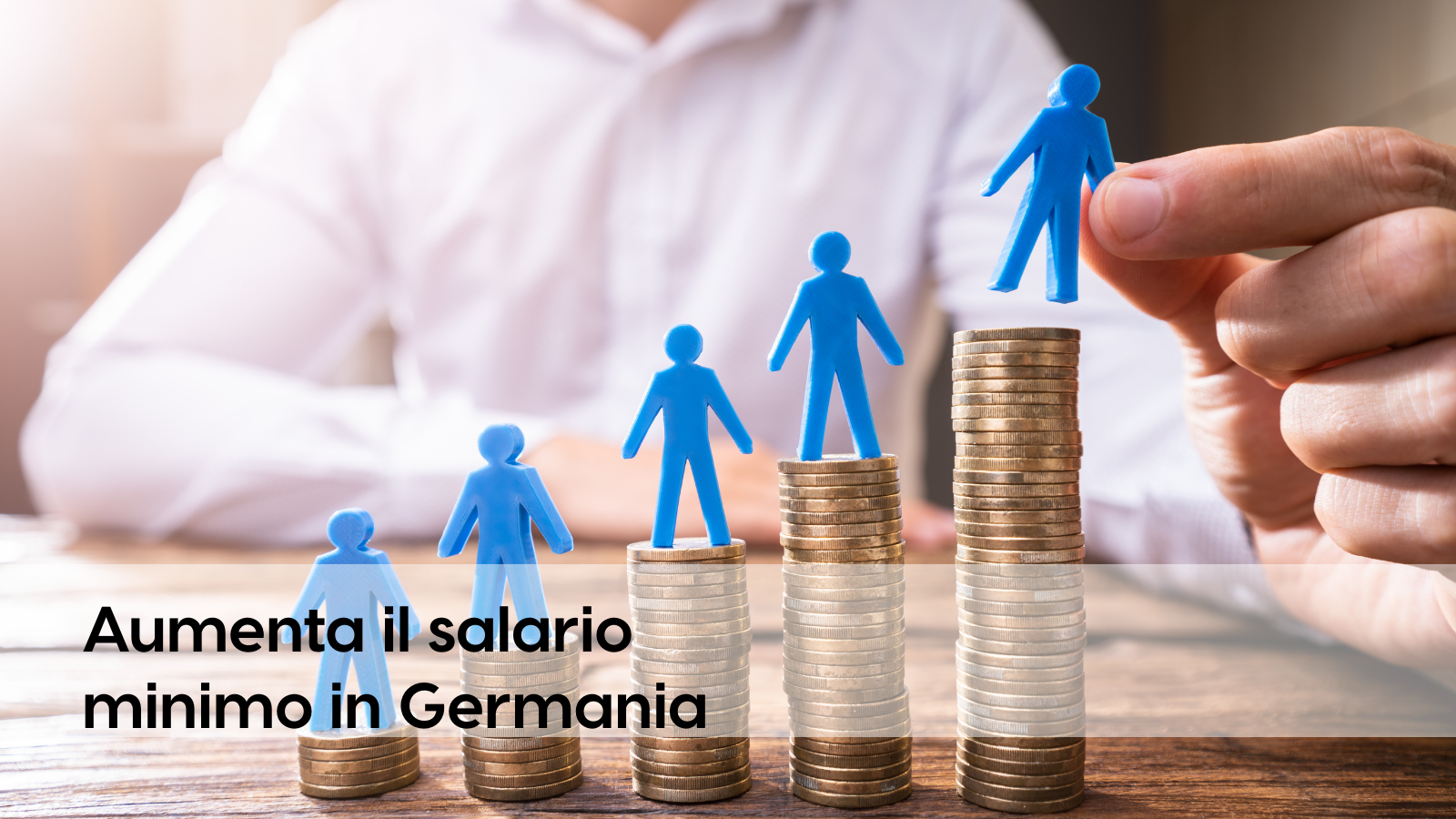 Blaue Figuren auf Münzstapeln symbolisieren den steigenden Mindestlohn in Deutschland und die wachsende Bedeutung von Kosten- und Produktivitätstransparenz, etwa durch datenbasierte Analysen mit profitize.