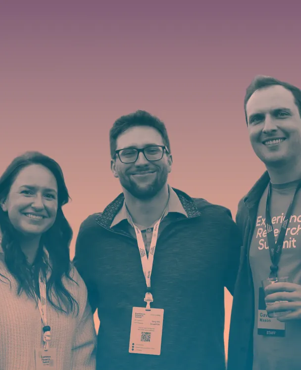 Three smiling people wearing name badges at an event, standing against a gradient background.