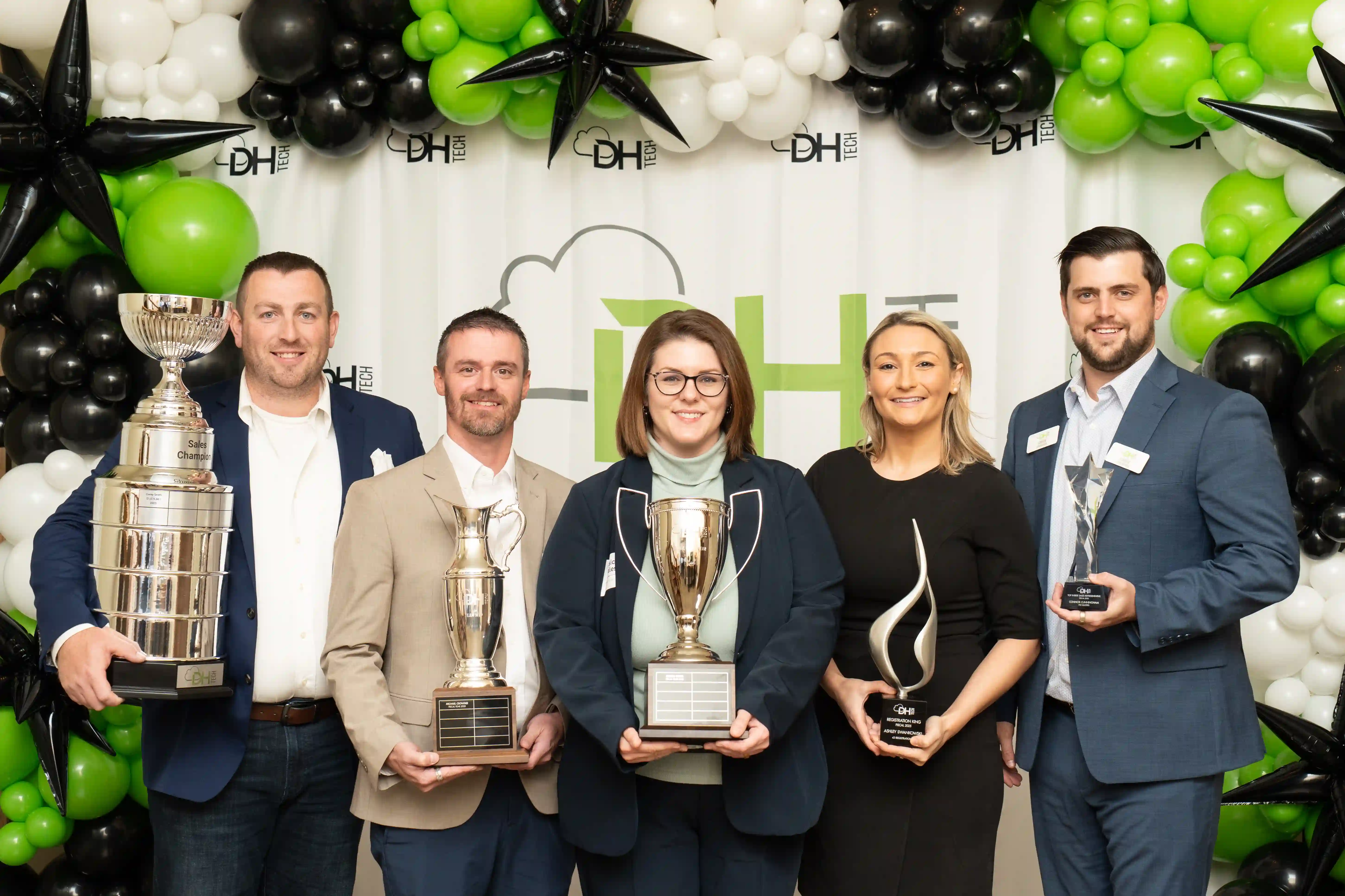 5 employees with various company awards in front of DH Tech Step and Repeat banner