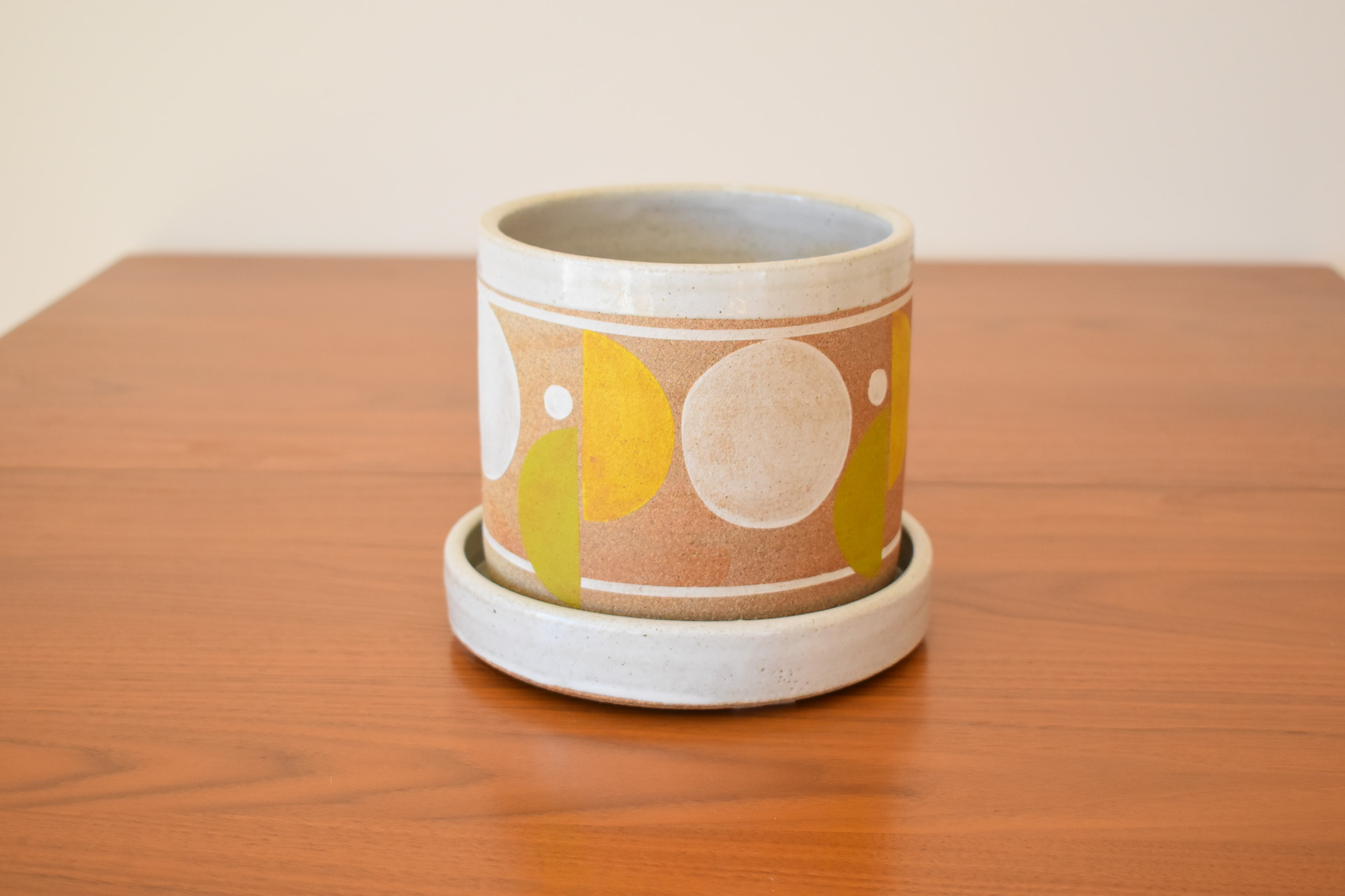 Wheelthrown with stoneware and hand painted using non-toxic underglazes and a white glossy glaze. Planter measures 5.5" tall x 6" wide. Base measures 7" wide x 1.25" tall.