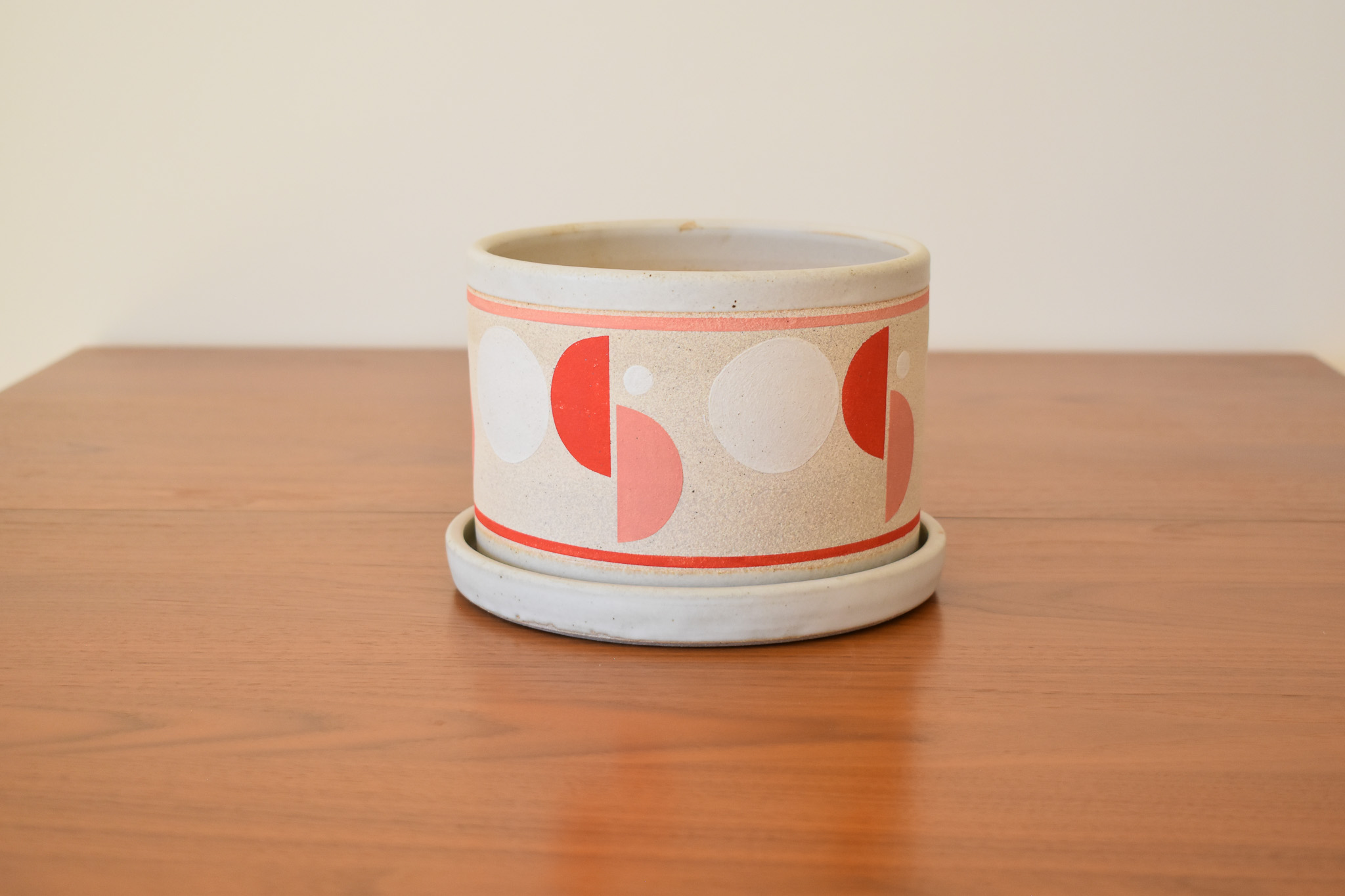 Wheelthrown with stoneware and hand painted using non-toxic underglazes and a white glossy glaze. Planter measures 7" tall x 5" wide. Base measures 8" wide x 1" tall.