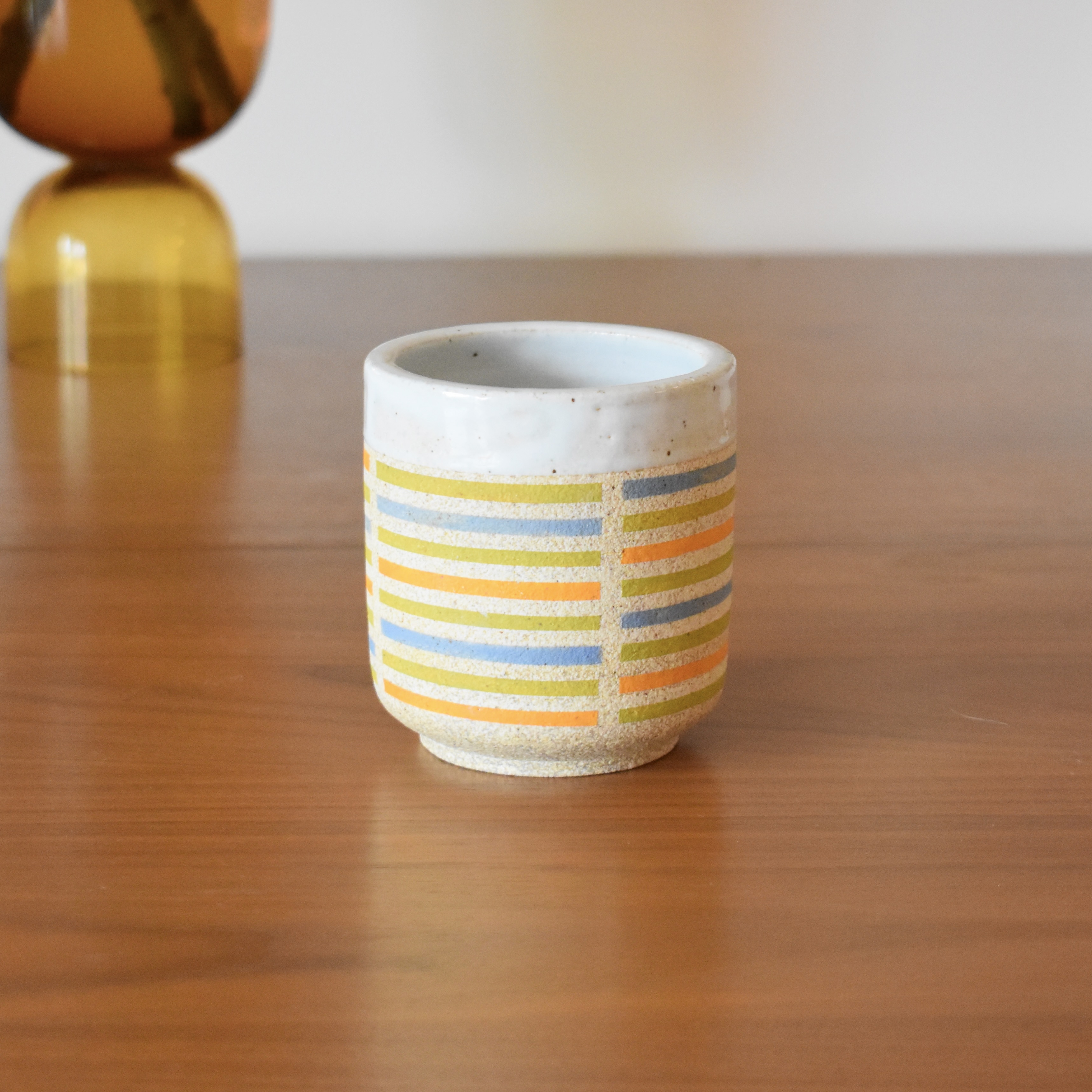 Wheelthrown with stoneware and hand painted using non-toxic underglazes. Glazed glossy white on the interior, and outer lip. 3.25" wide x 3.5" tall. Holds ~10 fl. oz.