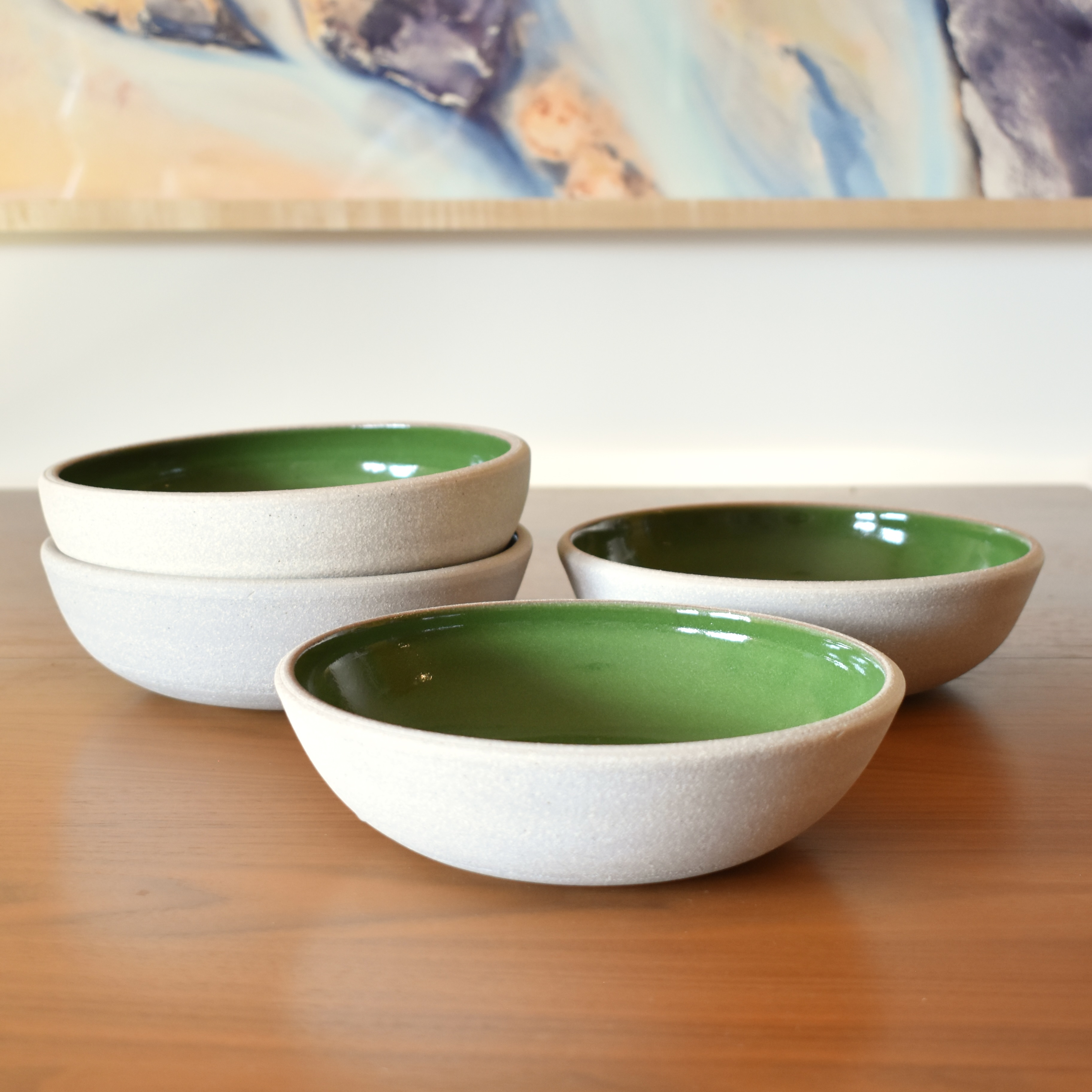 Wheelthrown with stoneware. Interior is glazed in a bright glossy green. Exterior and rim unglazed. Measure 8" wide x 2.25" tall. Sold as a set of 4. Please allow for variation in glaze and size as each piece is handmade. 