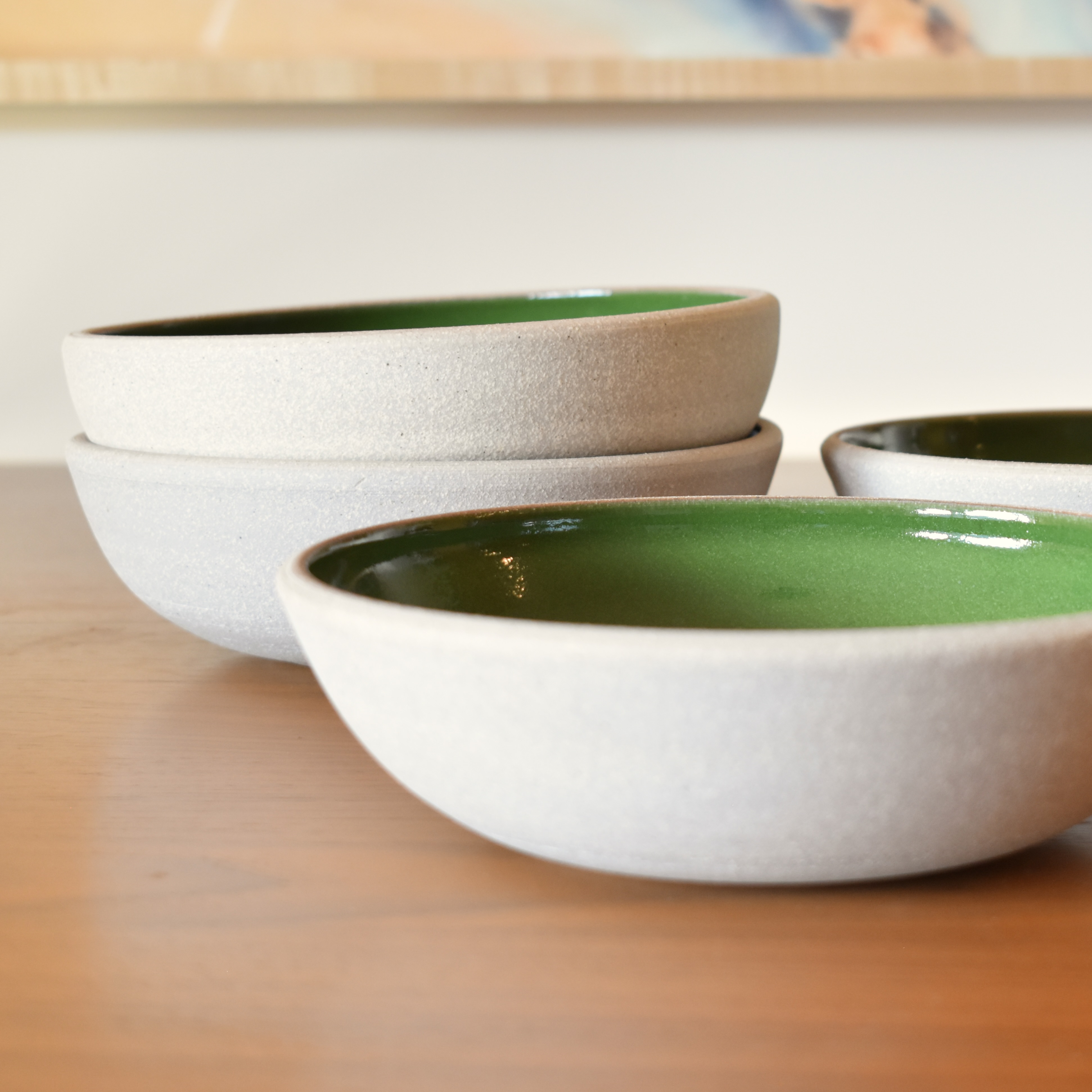 Wheelthrown with stoneware. Interior is glazed in a bright glossy green. Exterior and rim unglazed. Measure 8" wide x 2.25" tall. Sold as a set of 4. Please allow for variation in glaze and size as each piece is handmade. 