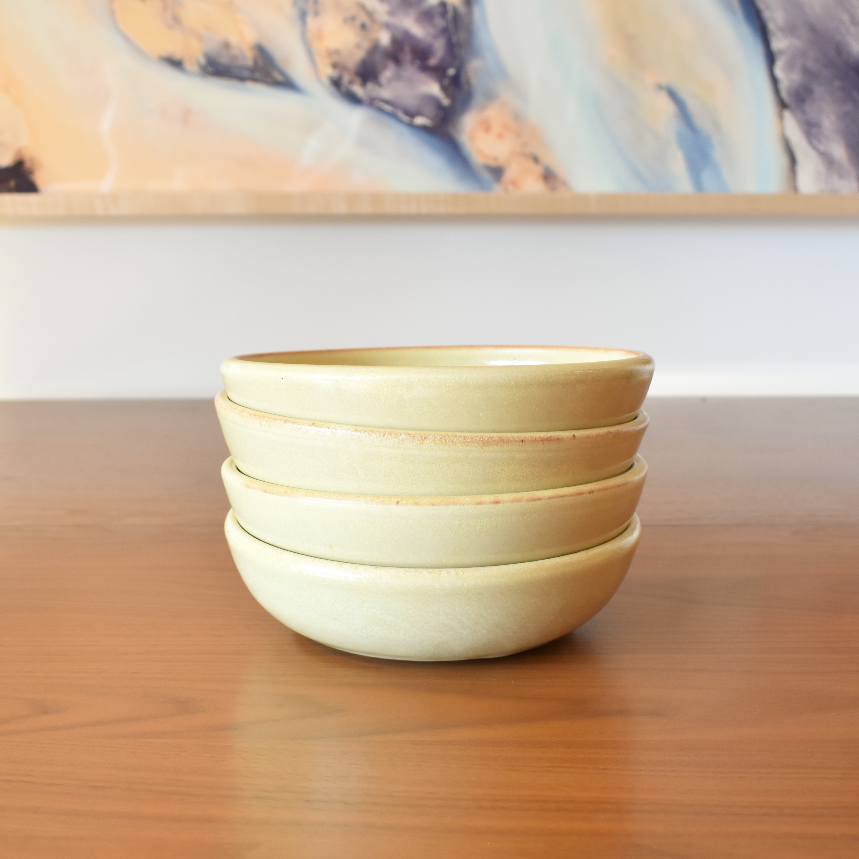 Wheelthrown with stoneware. Glazed in a pale yellow glossy glaze. Measure ~8" wide and 2.25" tall. Sold as a set of 4. Please allow for slight variation in glaze and size as each piece is handmade. 