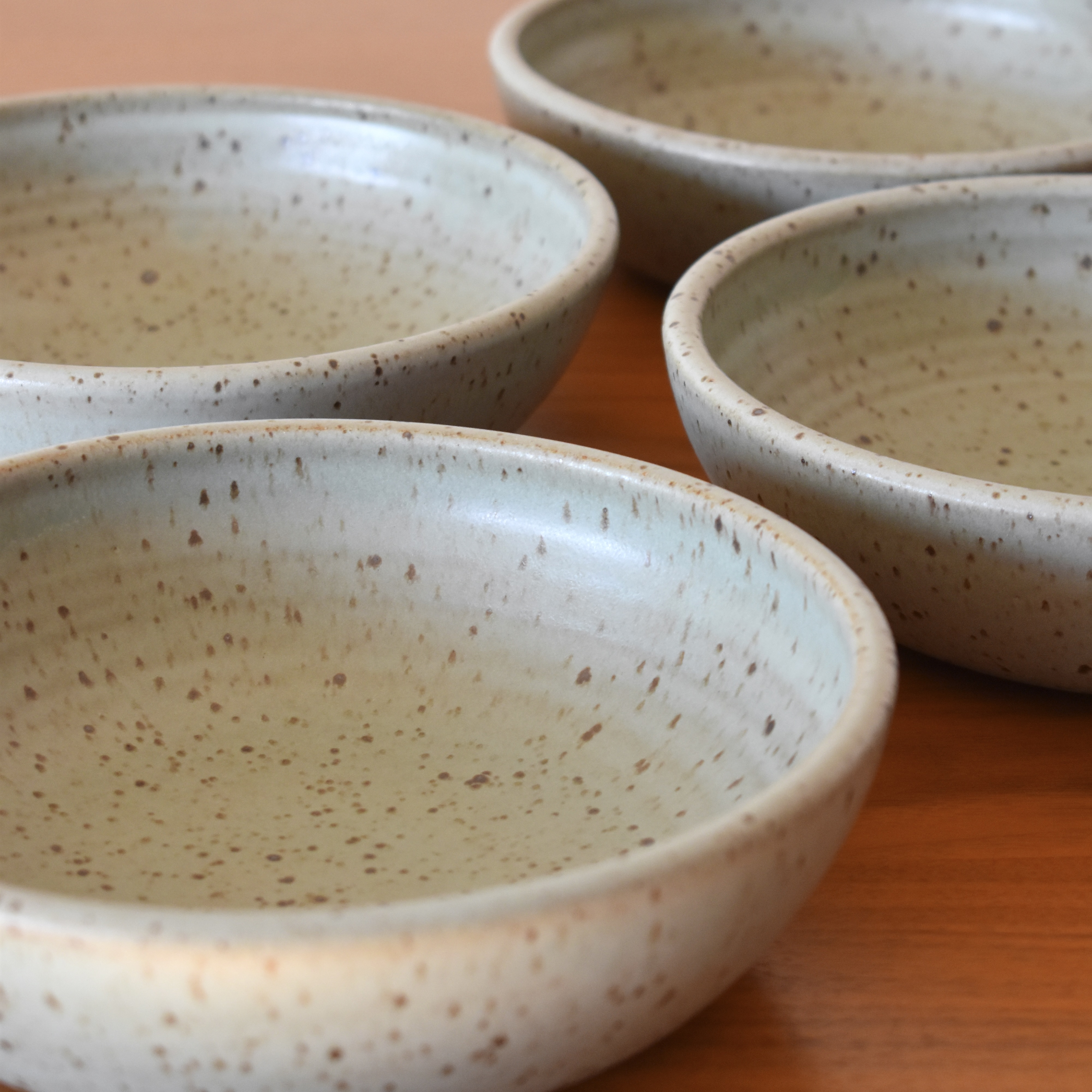 Wheelthrown with stoneware, and glazed in an eggshell blue speckled glaze. Sold as a set of 4. Each bowl measures ~8" wide x 2.25" tall. 