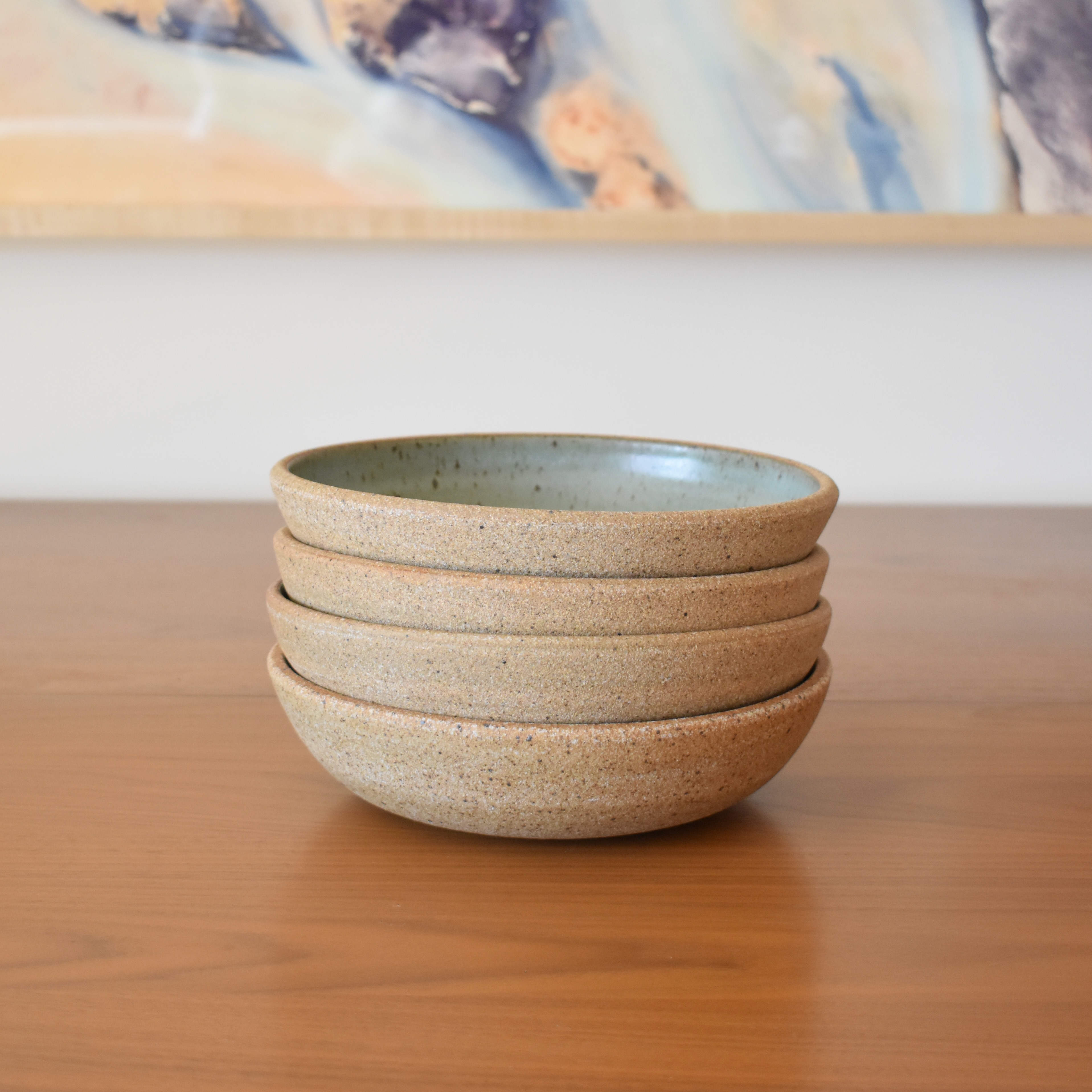 Wheelthrown with stoneware, and glazed in an eggshell blue speckled glaze. Rim & exterior are unglazed, showcasing a light brown claybody with variant iron speckling. Each bowl sold individually. Measures 8" wide x 2.25" tall. Please allow for slight variation in glaze and size as each piece is handmade.