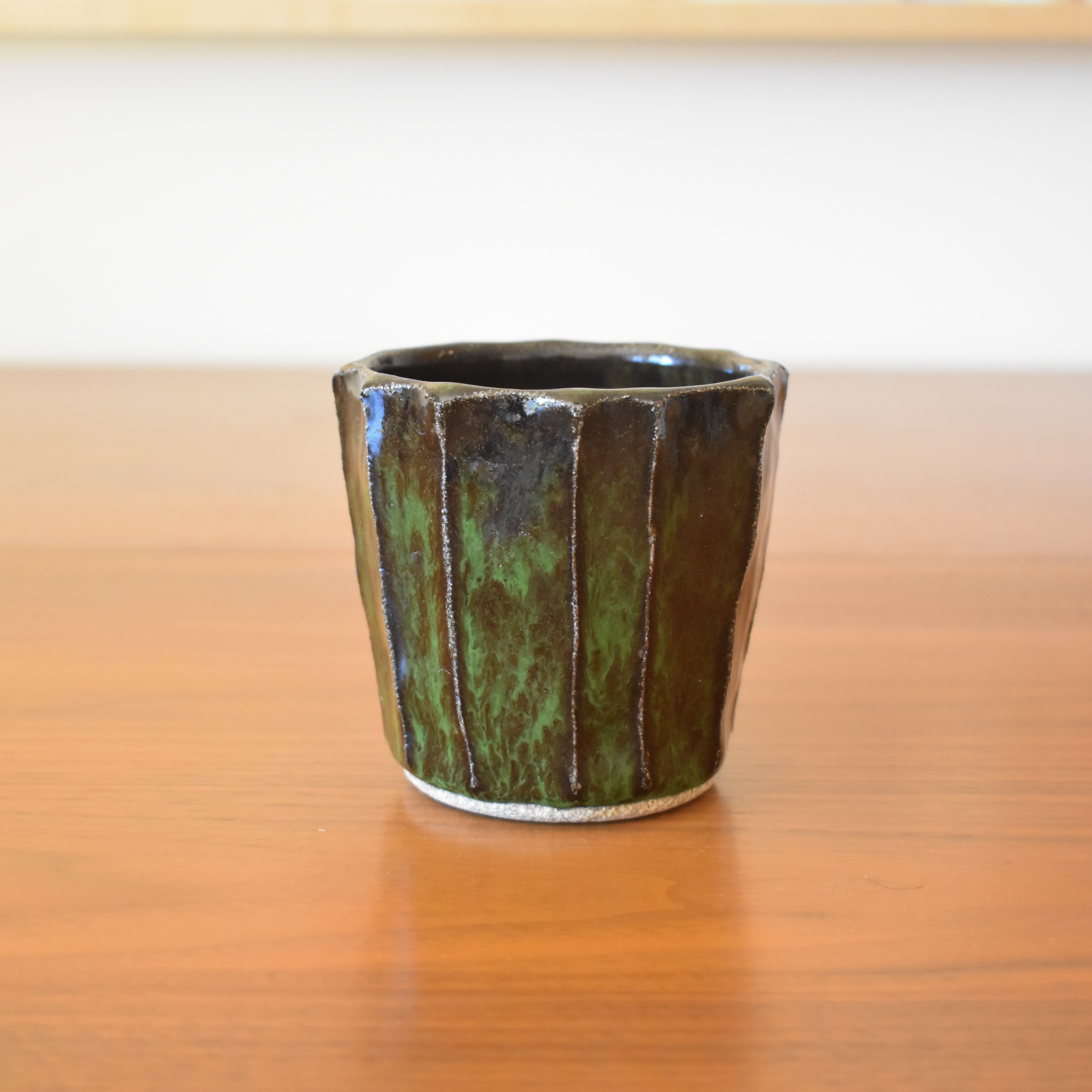 Wheelthrown with stoneware and then hand carved for a faceted look. Glazed in a glossy black / green. 3.5" wide x 3.25" tall. Hold approximately 12 fl oz. 