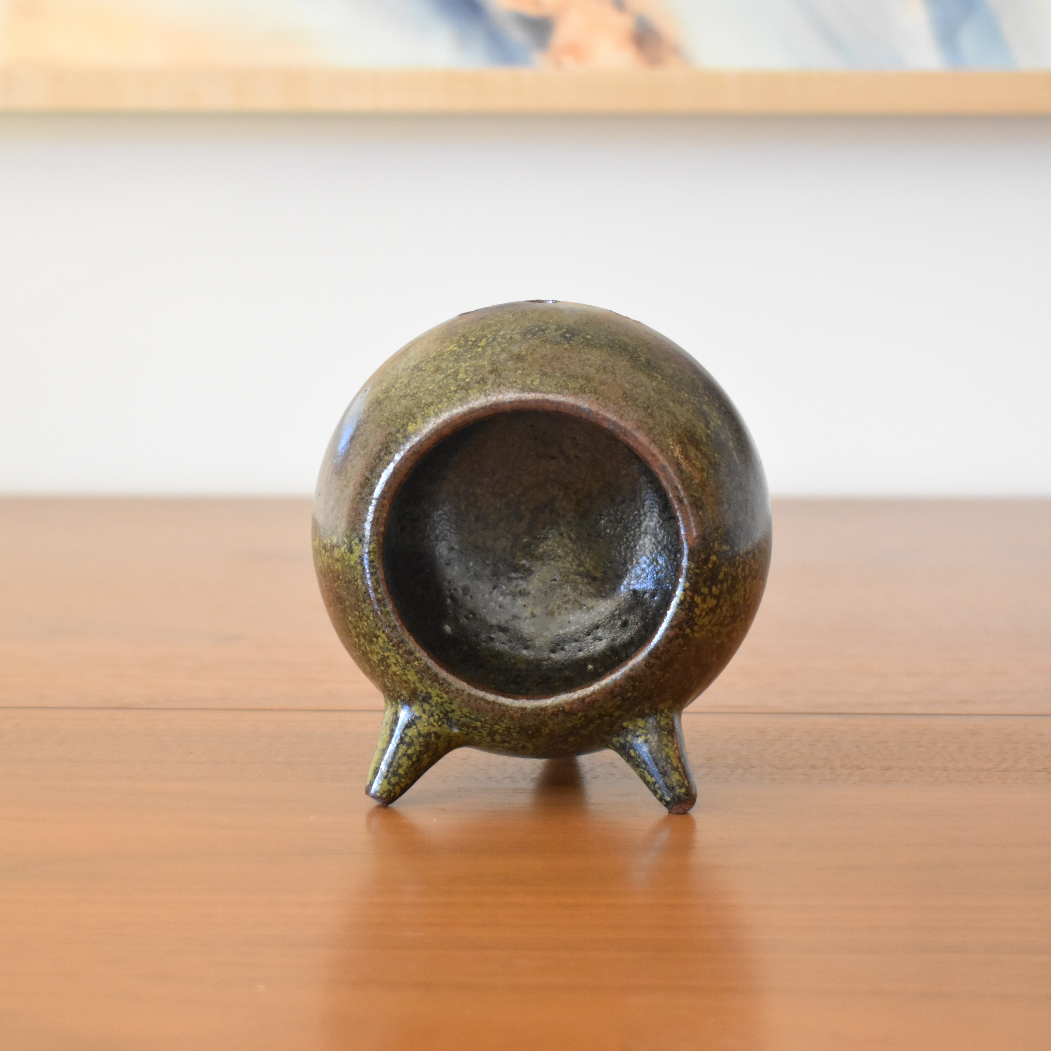 Wheelthrown with stoneware and hand-built feet. Glazed in a green speckled black/brown glaze. Measures 4.75" tall.