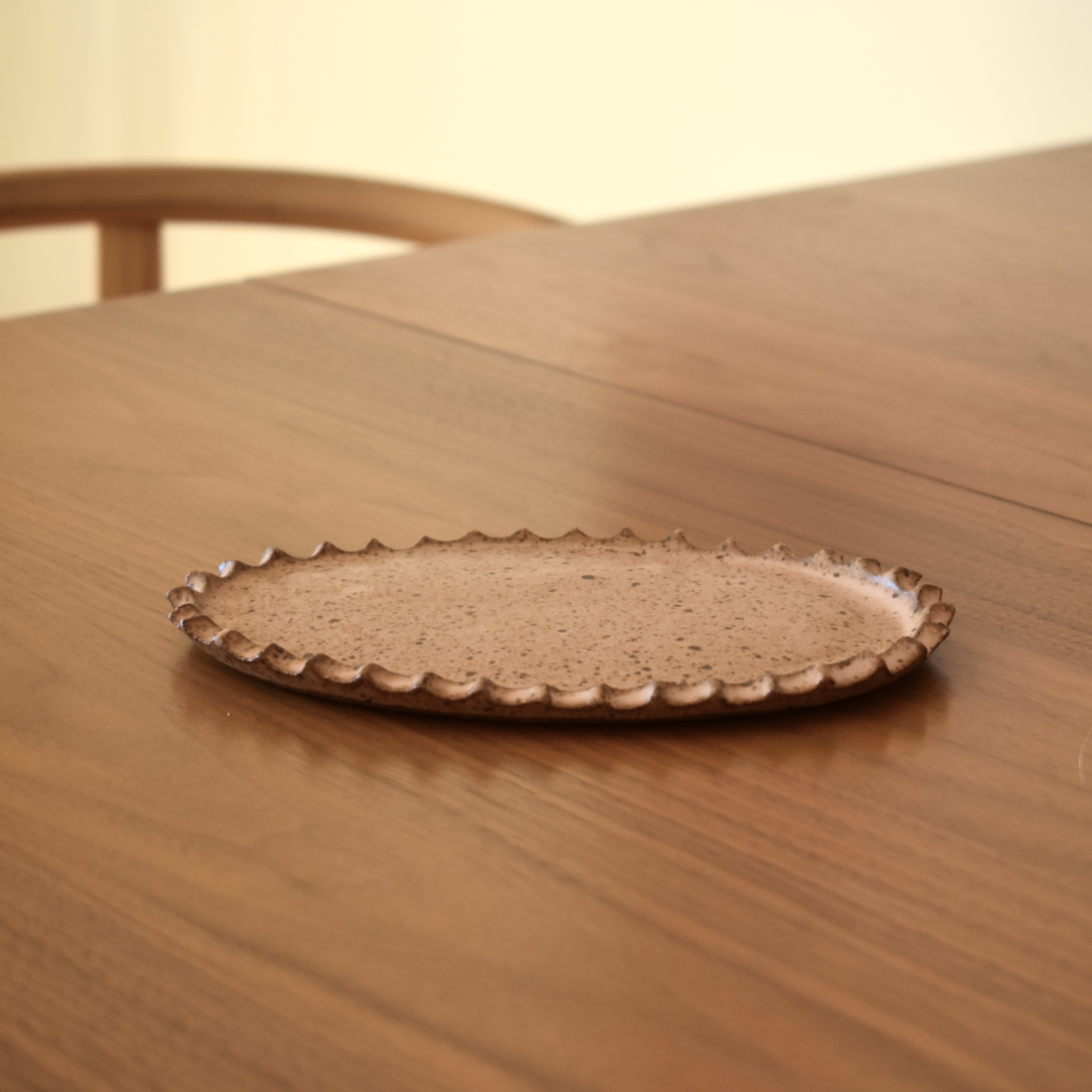 A handbuilt tray in a speckled pink. 7.5" long x 5" wide.
