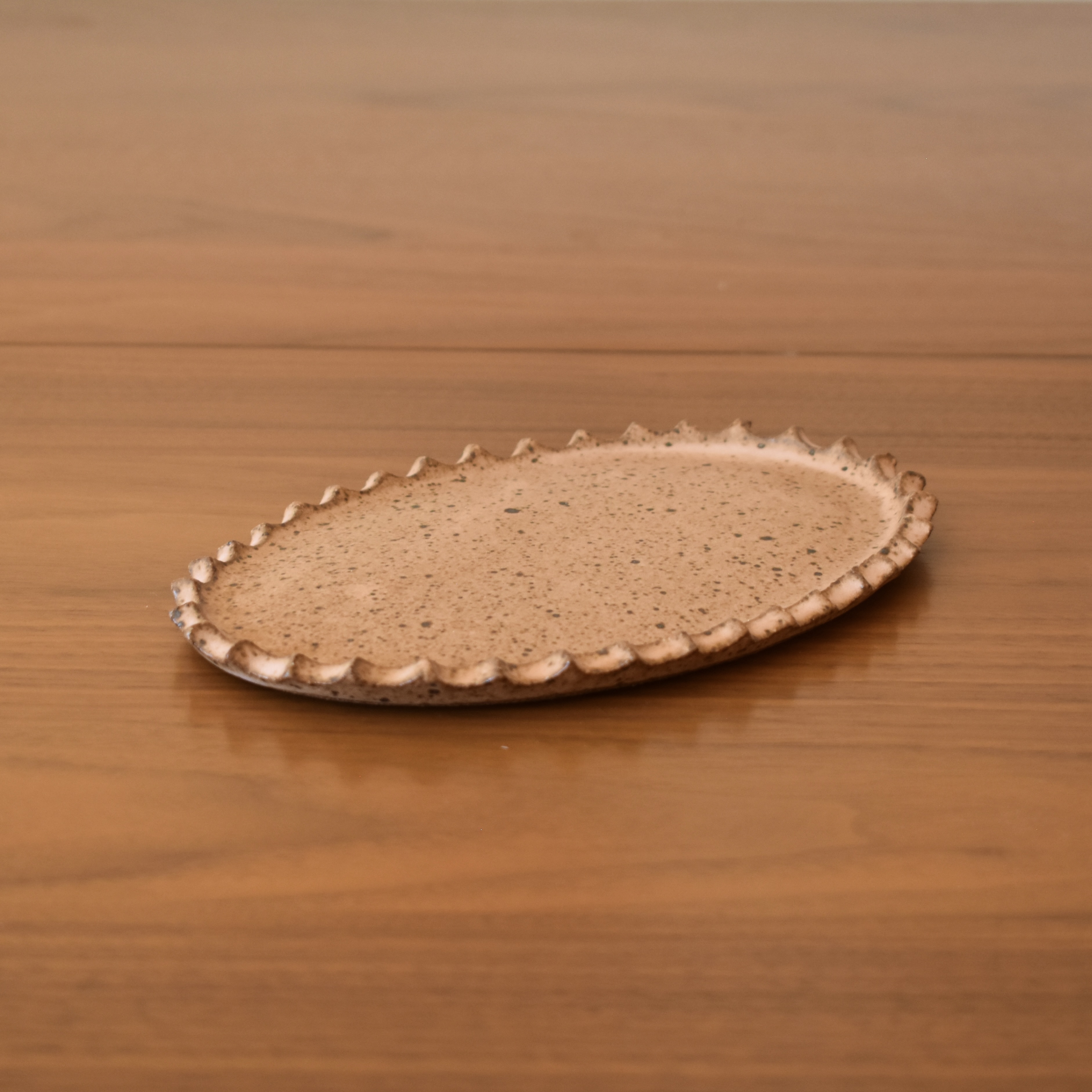 A handbuilt tray in a speckled pink. 7.5" long x 5" wide.
