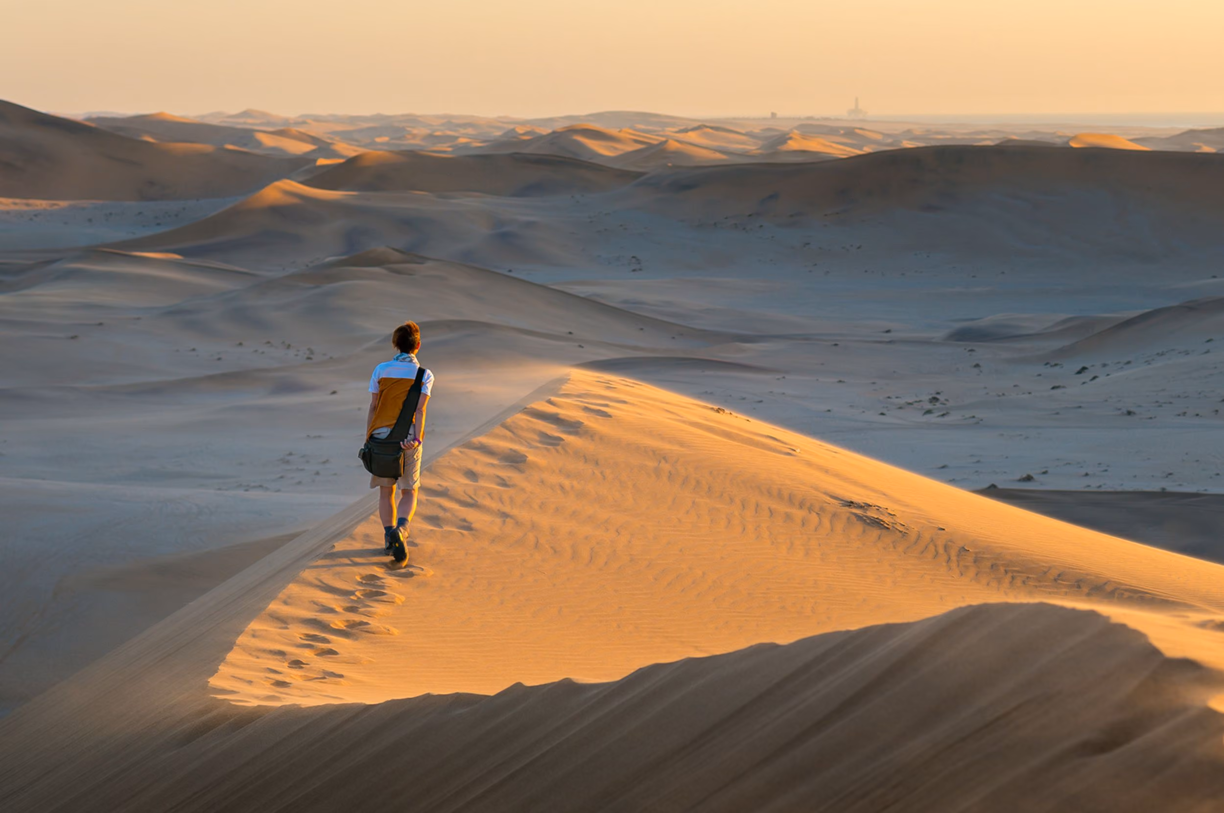 A man walks along the golden dunes of Sossusvlei, Namibia.