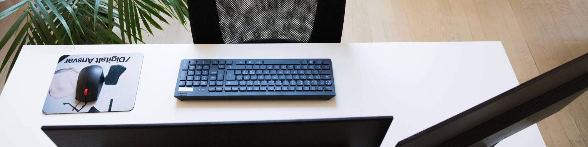 En tom kontorplads med tastatur og skærme