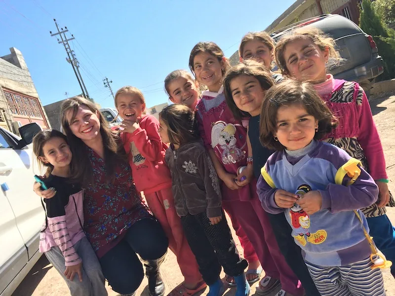 HUMANITE cofounder Jessica Courtney kneels in the street, surrounded by refugee children in Iraq. 