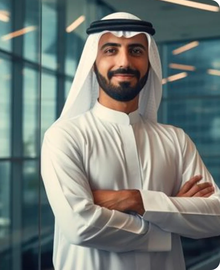 Smiling man in traditional Middle Eastern attire with arms crossed standing in a modern office.