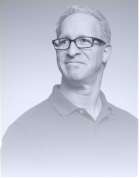 Man with short gray hair, glasses, and a light beard wearing a polo shirt, smiling slightly and looking to the side.