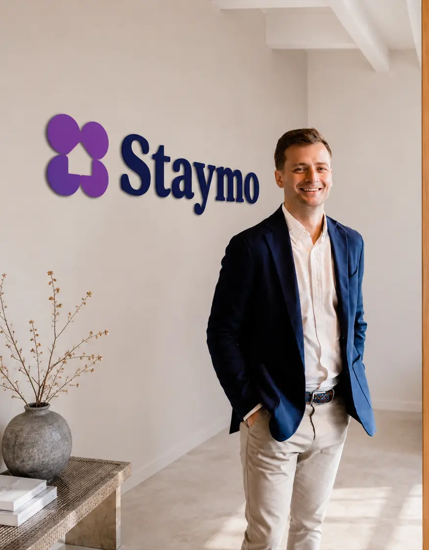 Staymo property expert standing in the office by the Staymo logo