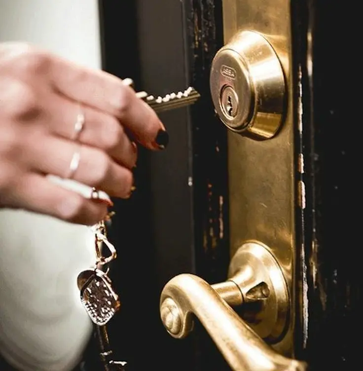 Hand unlocking a brass front door lock