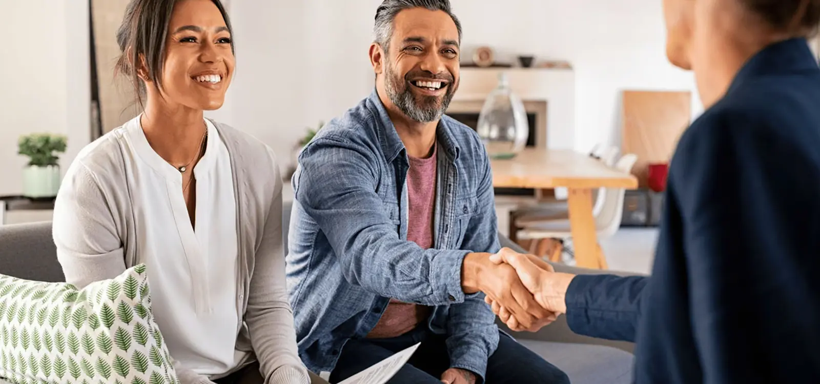 Two property owners shaking hands with a Staymo manager in a living room