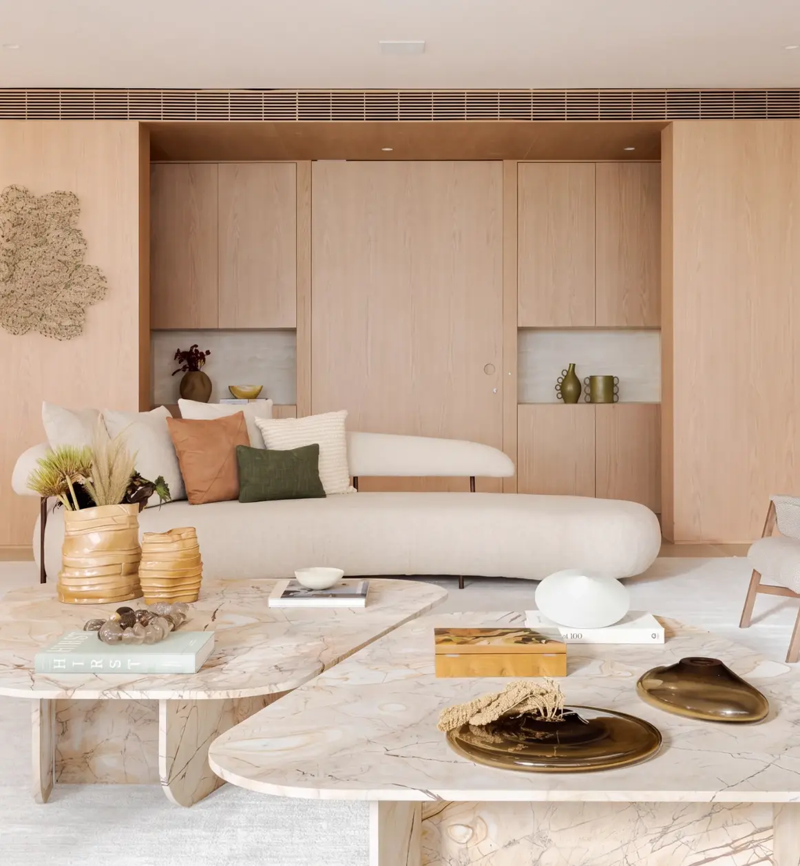 Living room with a curved sofa, oak panelling and marble coffee tables