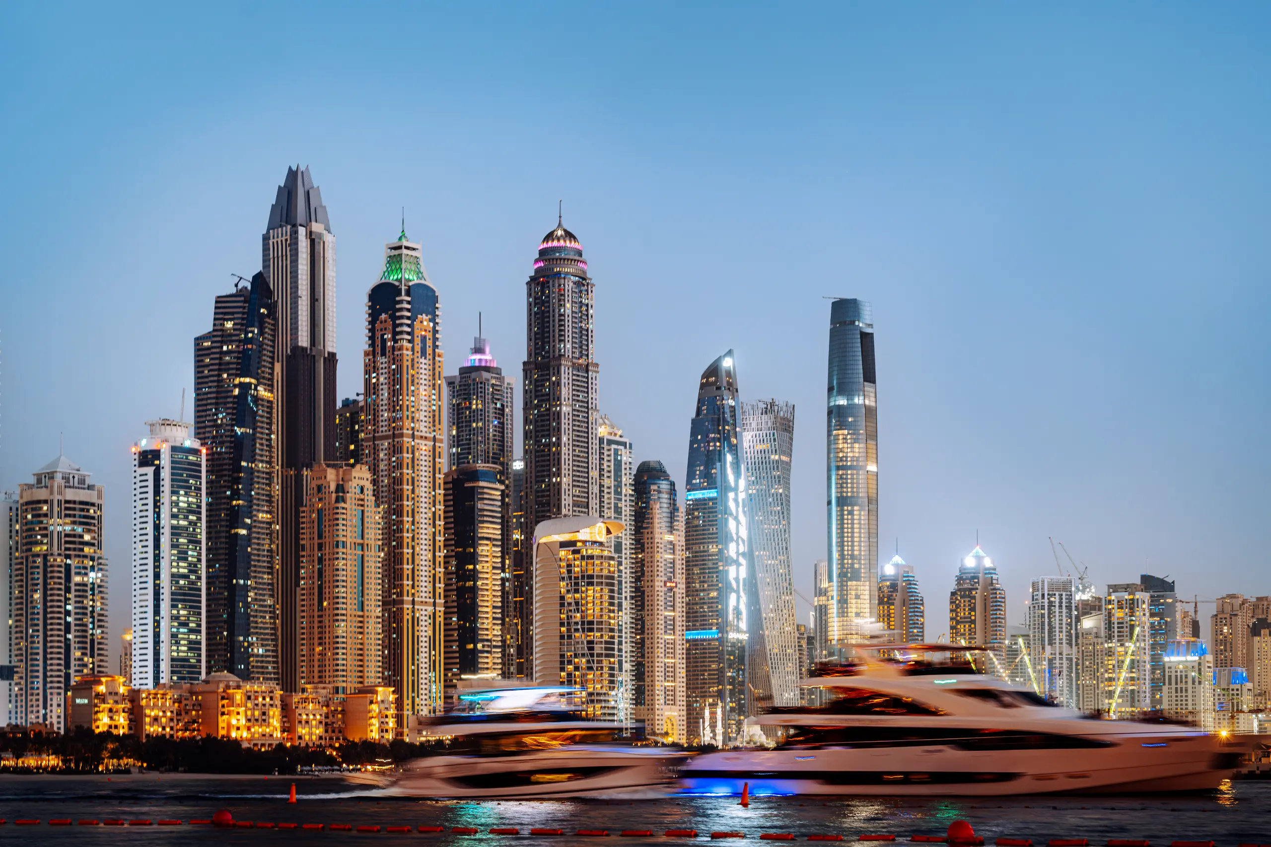 Dubai skyline at dusk, with yachts on the water