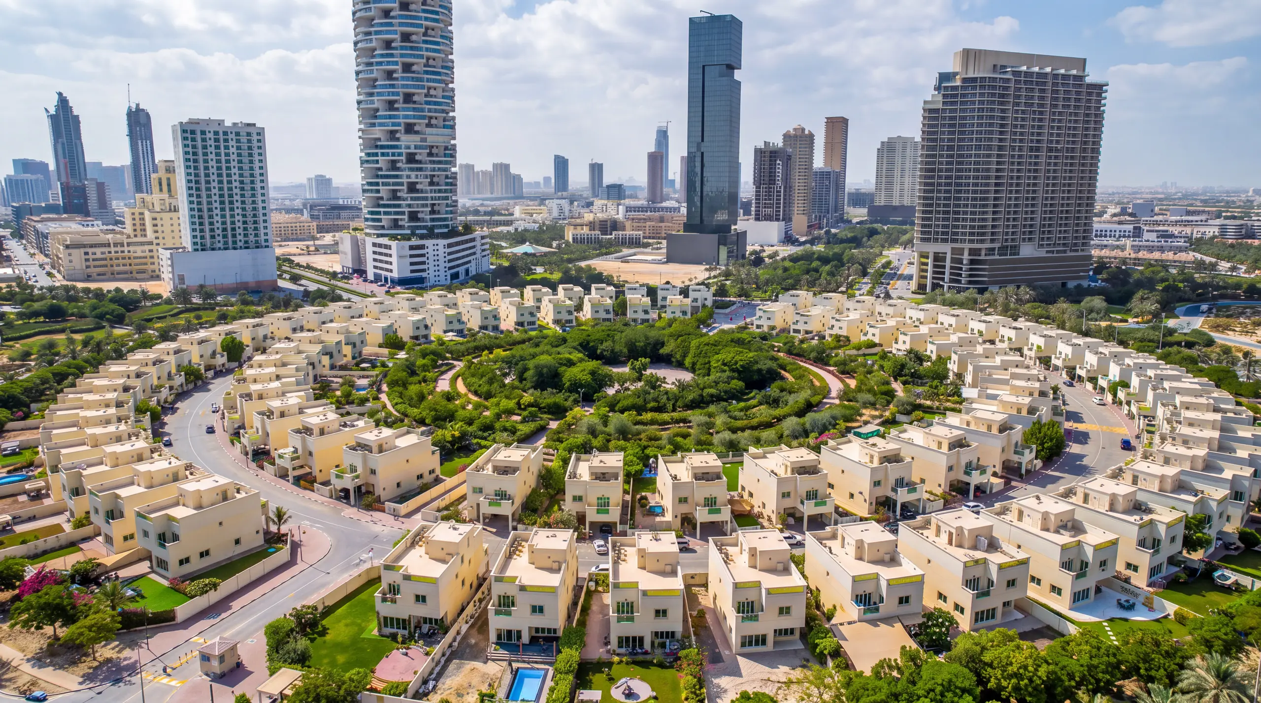 Jumeirah Village Circle from the air: villas around a central park, towers behind