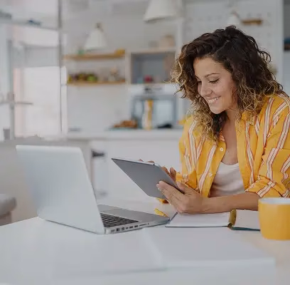 Host checking short-let bookings on a tablet beside her laptop