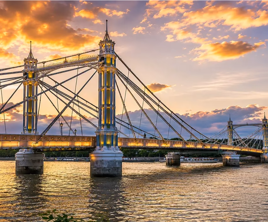 Albert Bridge lit up over the Thames under a golden sunset sky