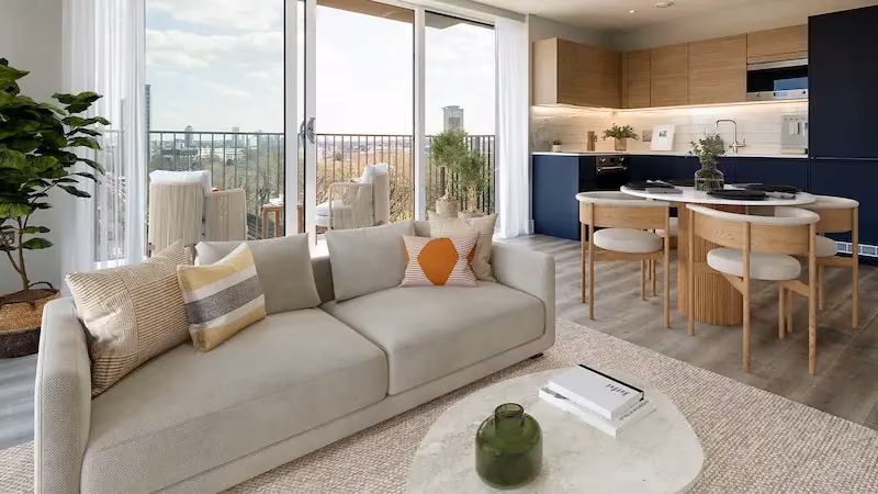 Bright apartment living area with sofa, dining set and kitchen with a city view through glass doors.