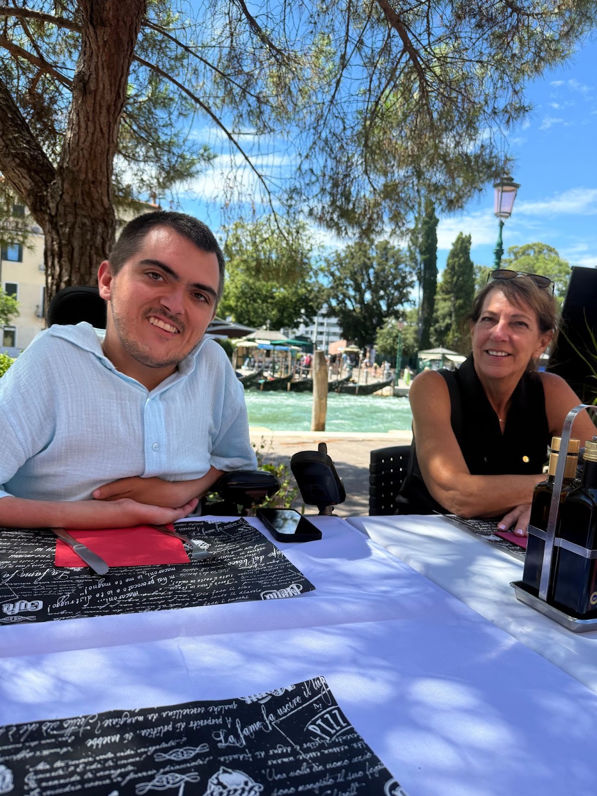 A man and woman sitting at a table with the Venice canal behind them