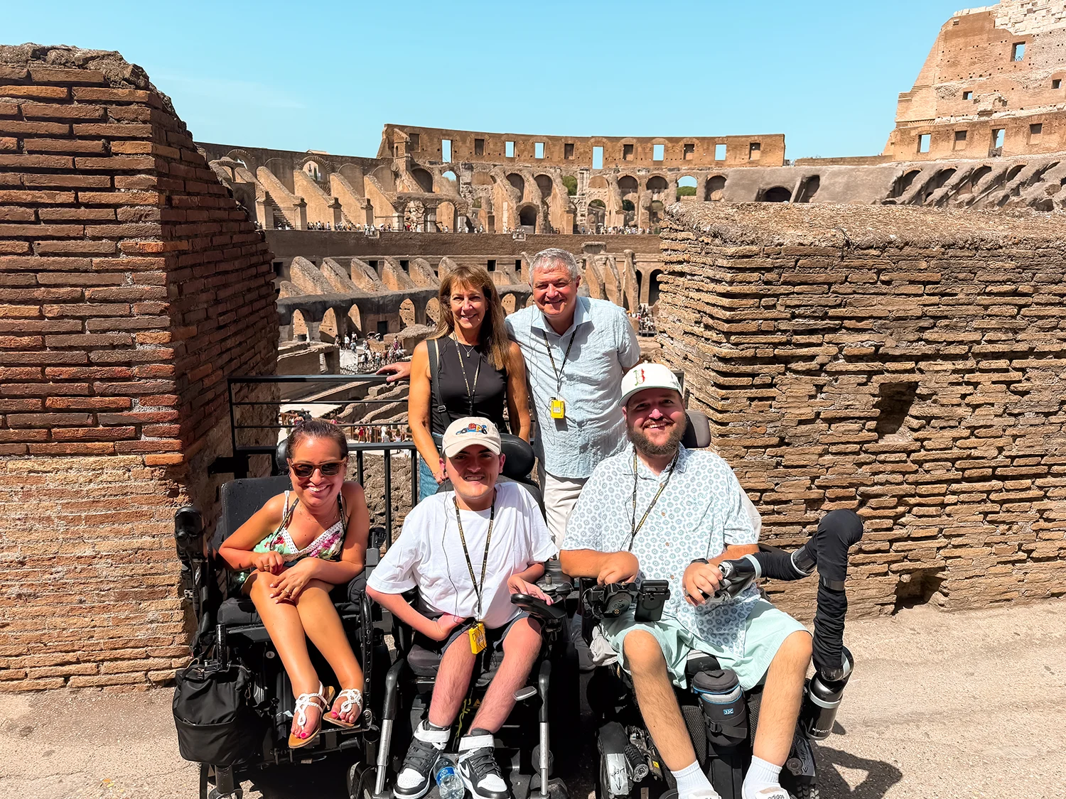 Family with two people standing and three people in wheelchairs inside the Roman Colosseum