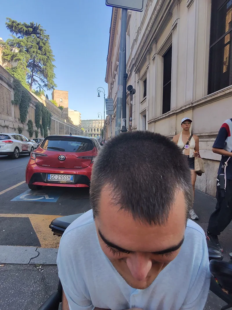 A man leaning over revealing the Roman Colosseum behind him