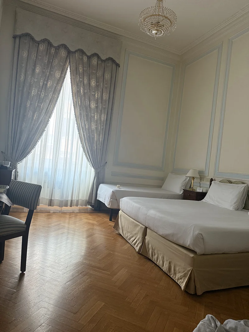 Hotel room with large ceilings, king size bed and a rollaway bed