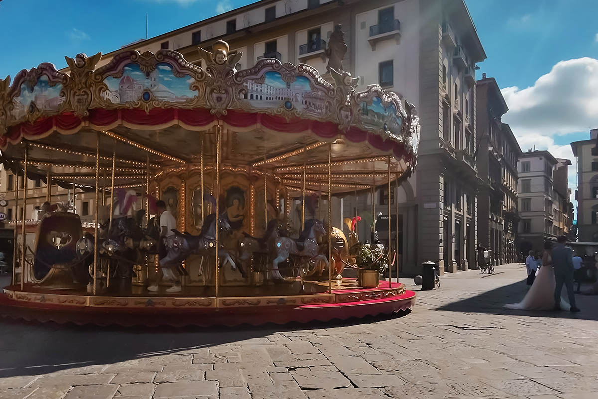 g vintage carousel in Piazza della Repubblica Florence with bride and groom posing for photo
