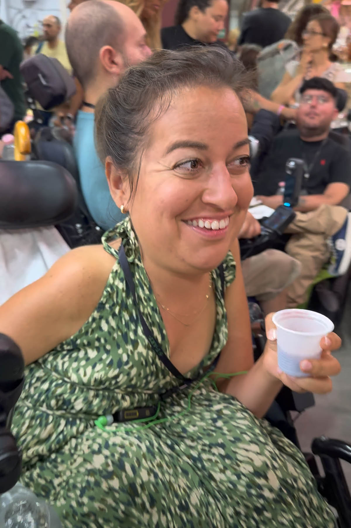 woman wearing a green dress smiling and holding a plastic cup of wine