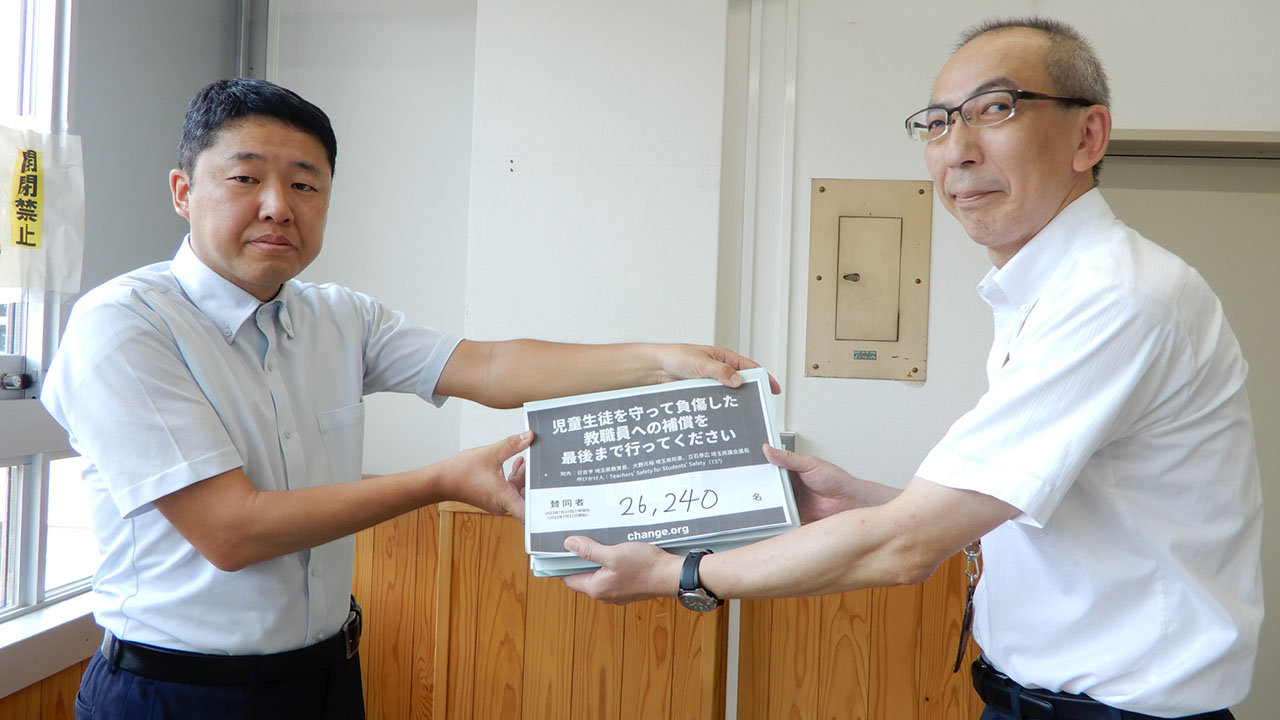 埼玉県教委の担当者に署名を提出する加藤教諭（左）