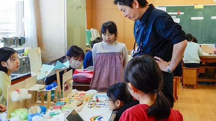 三越伊勢丹の仲田さんに相談しながらデザインを考えていく子どもたち＝撮影：松井聡美