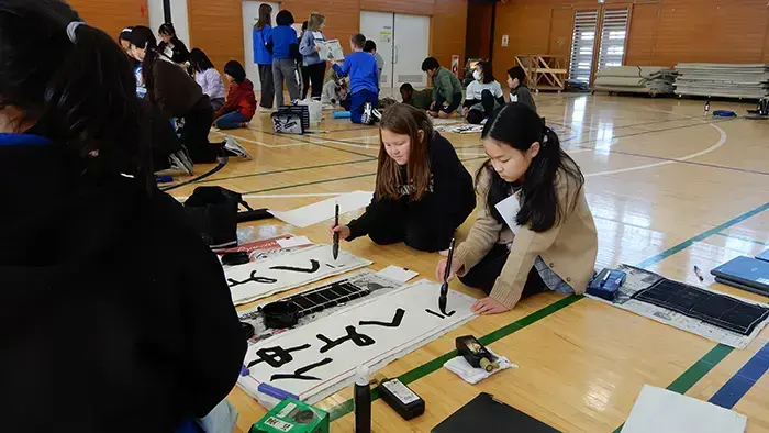 4年生が手本を見せながら、一緒に習字体験を楽しんだ＝撮影：松井聡美（プライバシー保護のため、画像の一部を加工しています）