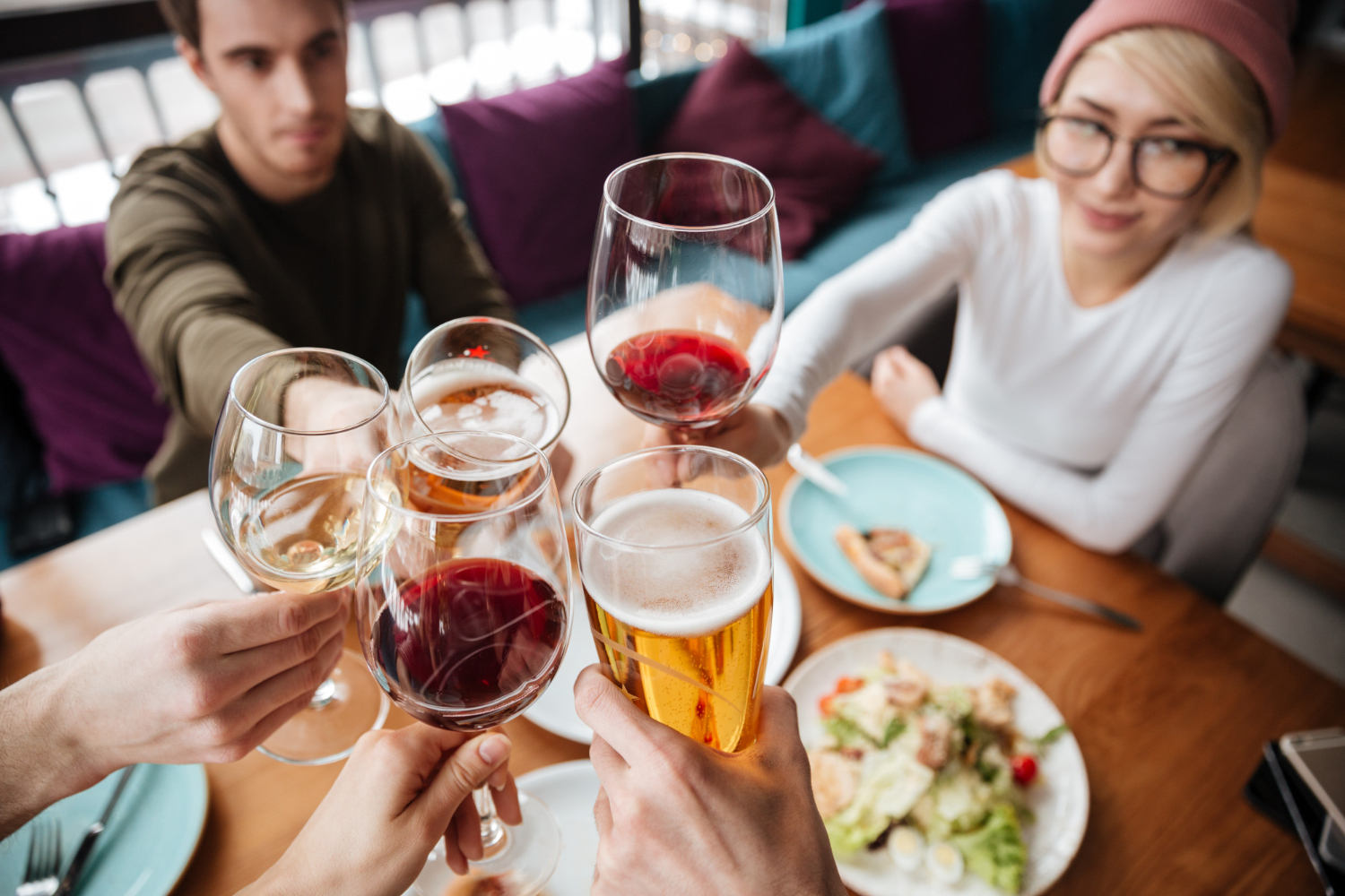 A group of friends cheers with their drinks over dinner.