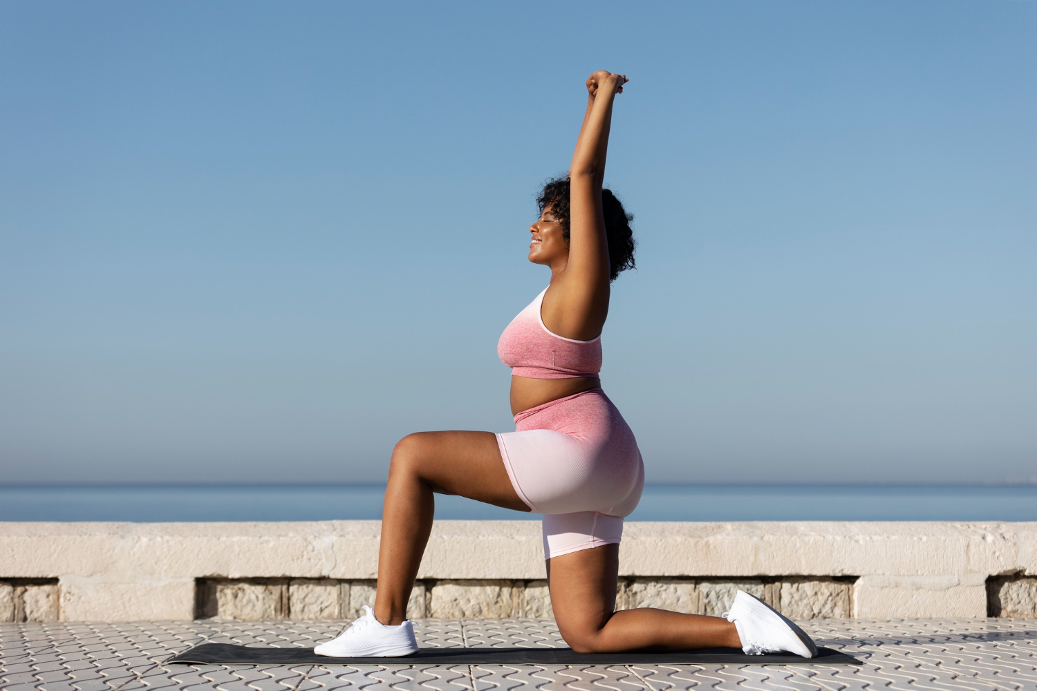 A woman does yoga on a beach on a clear, sunny day.
