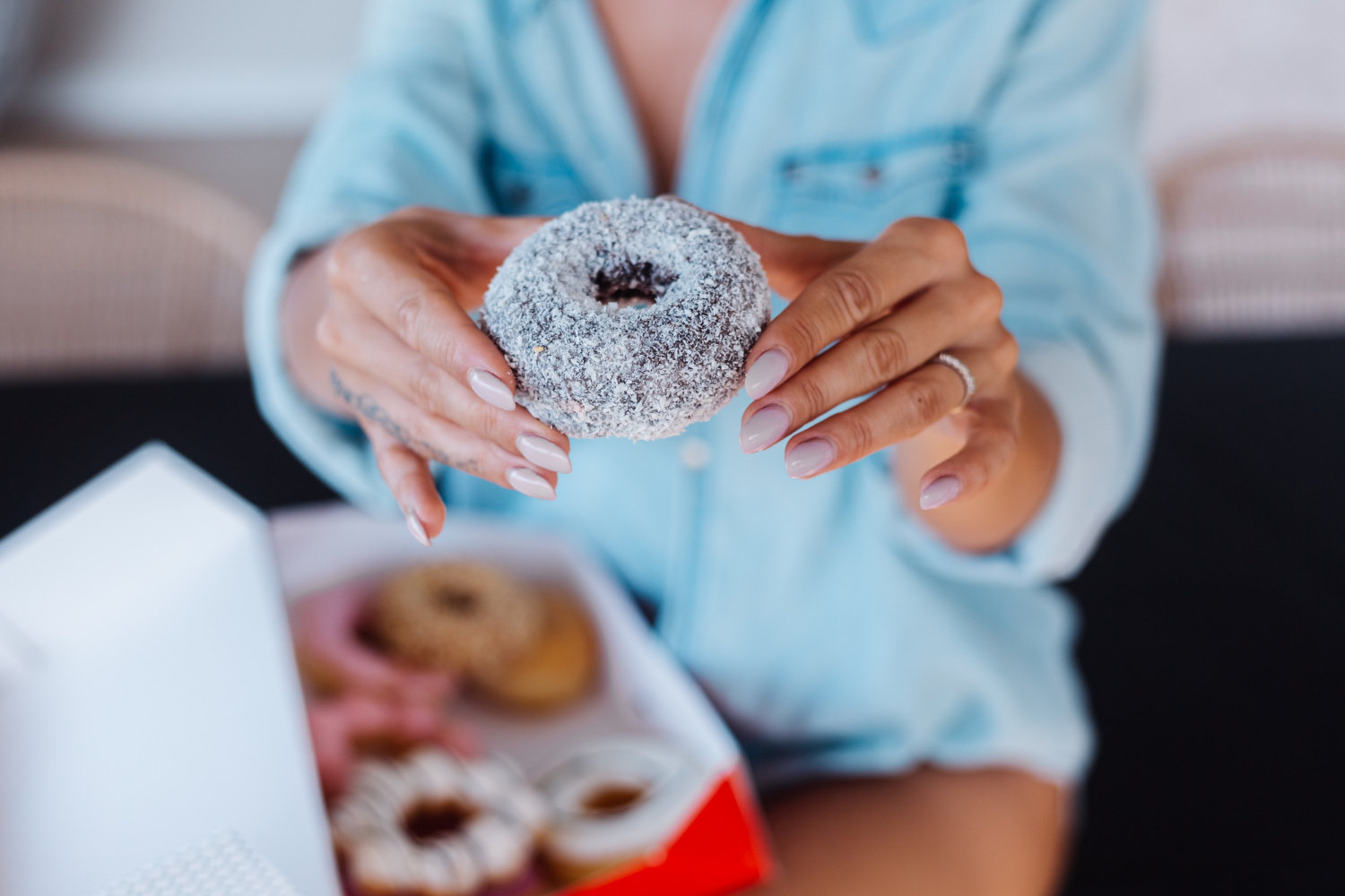 A woman holds a sugar-covered donut in her hands.