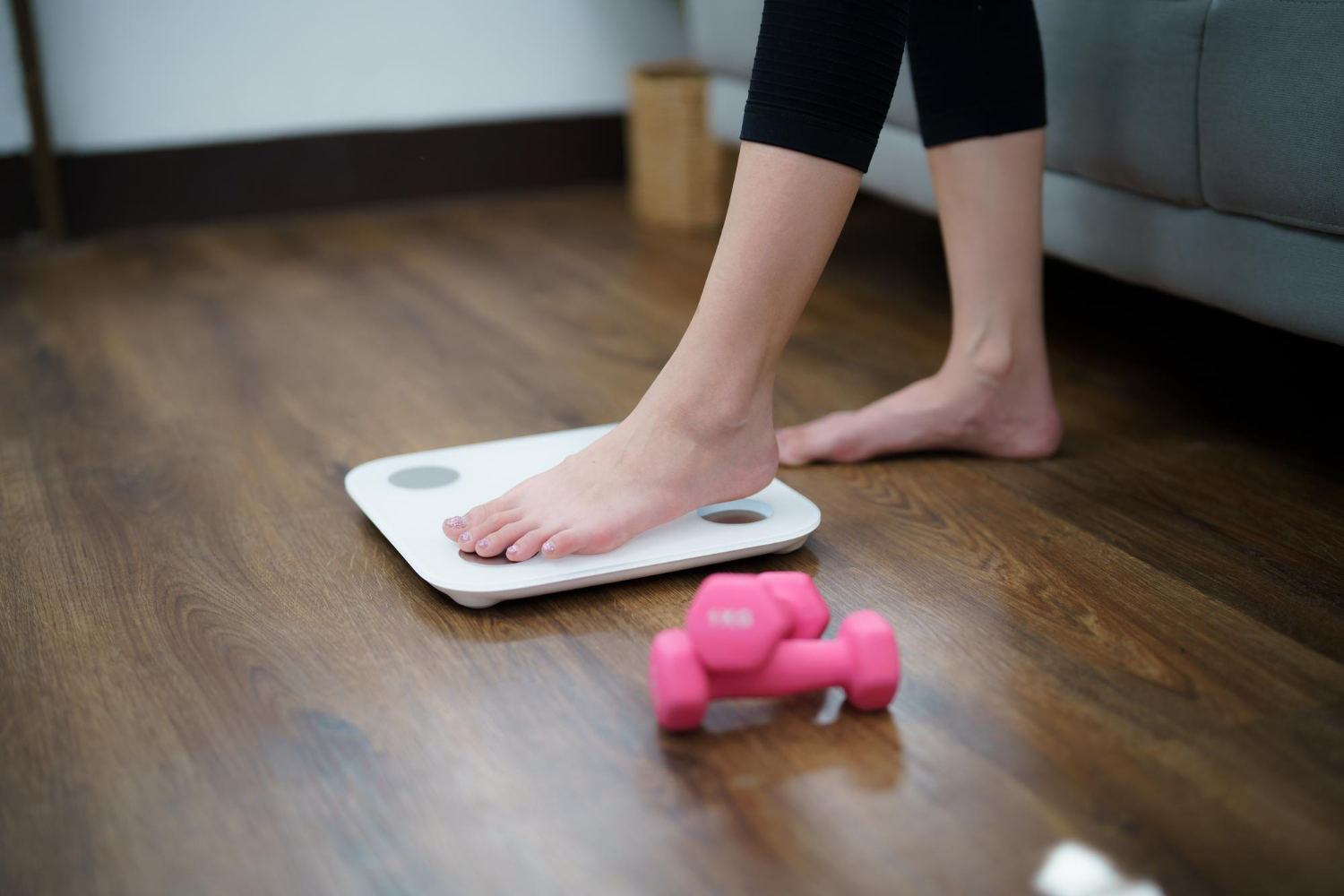 A image of a woman's feet as she steps onto a scale, preparing to weight herself.