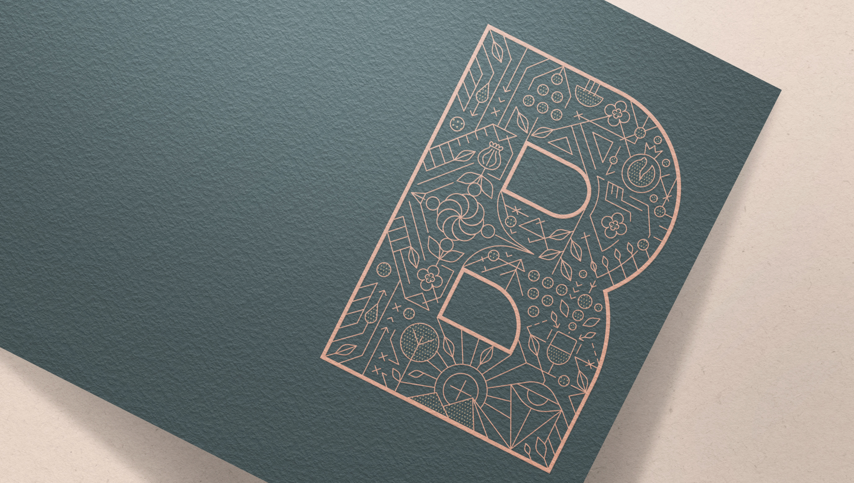 Ornate letter B filled with copper line-art pomegranates and vines on slate paper for Bariq winery by Lemoine.