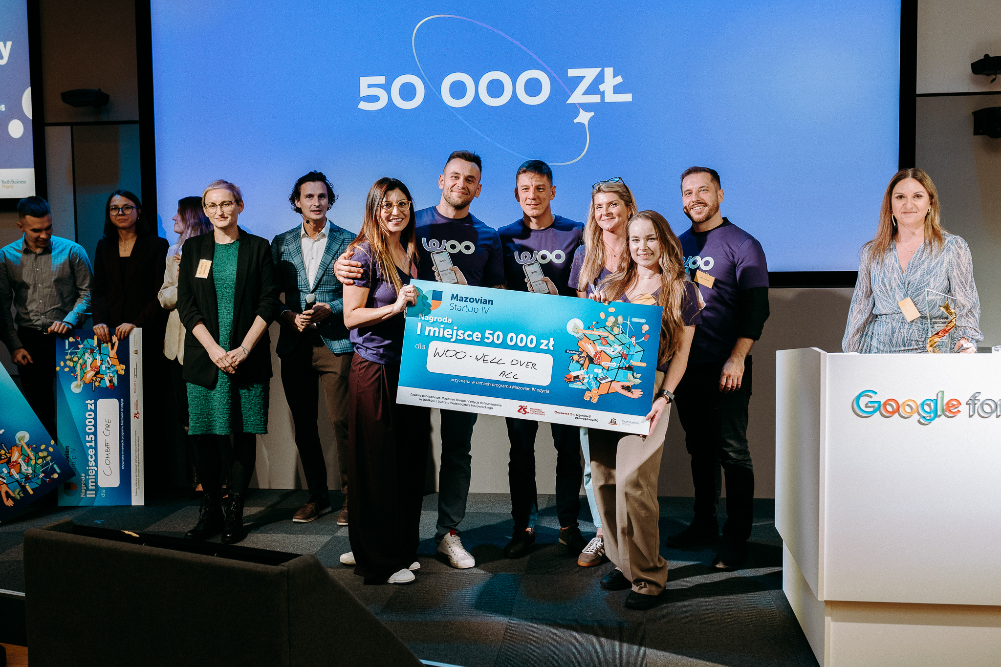 Grupa ludzi na scenie z nagrodą 50 000 zł za pierwsze miejsce w konkursie Mazovian Startup IV, ujęcie w Google for Startups.
