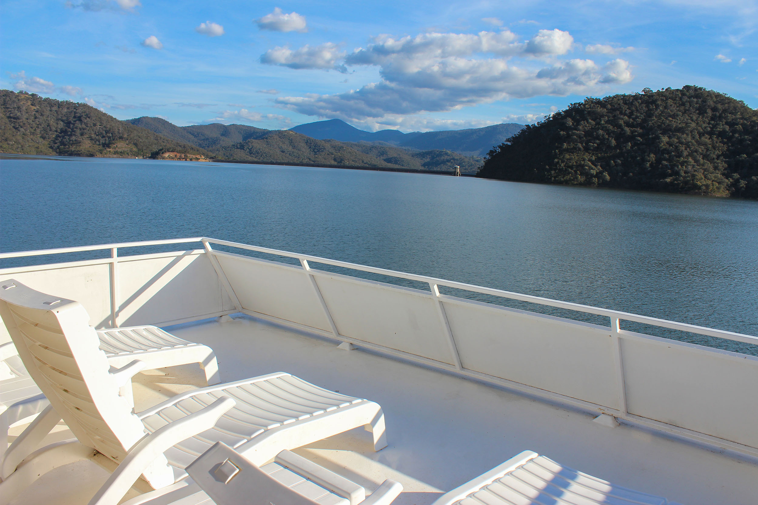 View from the rooftop deck of white sun lounges overlooking the lake, hills and distant mountains.